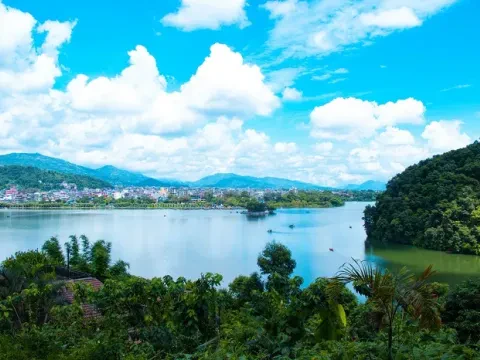 Scenic Phewa Lake with green hills and Himalayan mountain views in Pokhara, Nepal.
