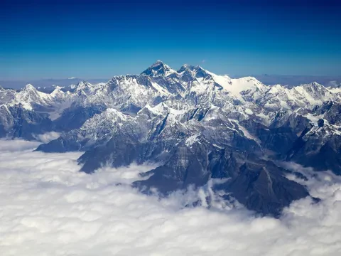 Snow-covered Himalayan mountains rising above a sea of clouds during an Everest mountain flight in Nepal.