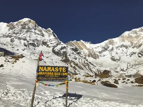 Annapurna Base Camp surrounded by snow-capped Himalayan mountains .
