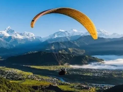 Paragliding above Phewa Lake in Pokhara with beautiful lake and Himalayan scenery.