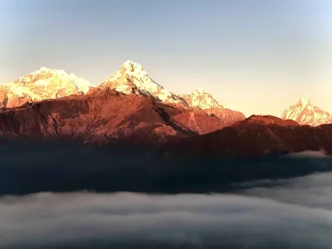Sun rays illuminating Annapurna South above clouds.