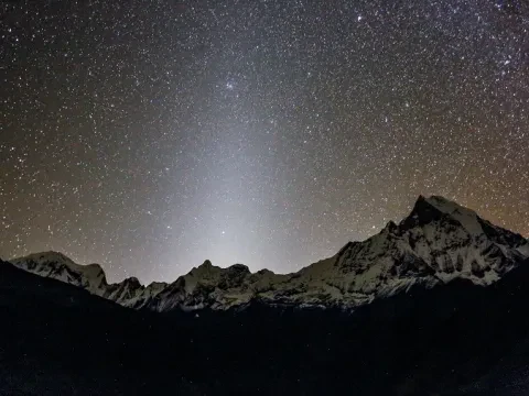 Star-filled night sky above Annapurna Base Camp with towering Himalayan mountains in Nepal.