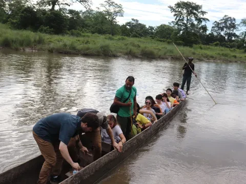 Traditional wooden canoe on the Rapti River in Chitwan National Park, Nepal, surrounded by lush riverbanks and natural jungle scenery.