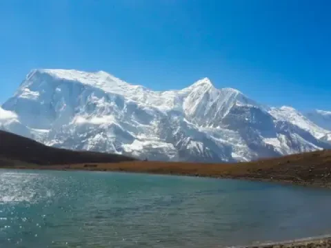 Ice Lake near Manang surrounded by snow-covered Himalayan mountains on the Annapurna Circuit Trek.