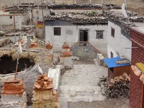 Traditional mud-brick village houses, with the rugged Himalayan mountains in the background.
