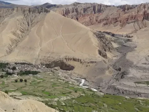 Traditional farmland in Upper Mustang, Nepal, surrounded by a rugged alpine desert landscape and towering Himalayan mountains.