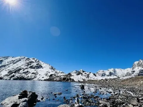 Clear blue water of Gosainkunda Lake surrounded by mountains.