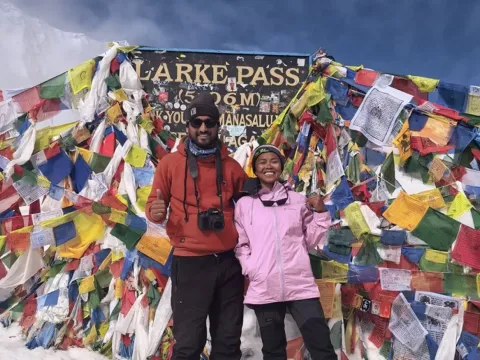 Trekkers standing at Larke Pass surrounded by snow-covered mountains on the Manaslu Circuit Trek.
