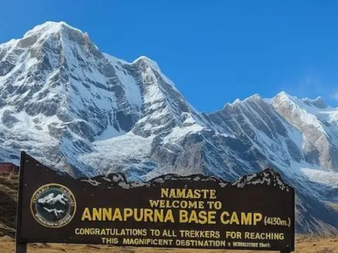 Annapurna Base Camp sign board surrounded by Himalayan mountains in Nepal.