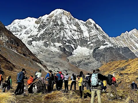 Trekkers walking along the trail to Annapurna Base Camp surrounded by Himalayan mountains in Nepal.