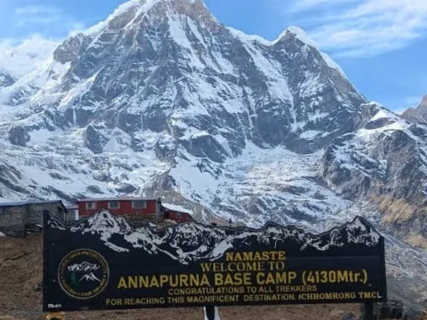 Annapurna Base Camp signboard surrounded by Himalayan mountains in Nepal .