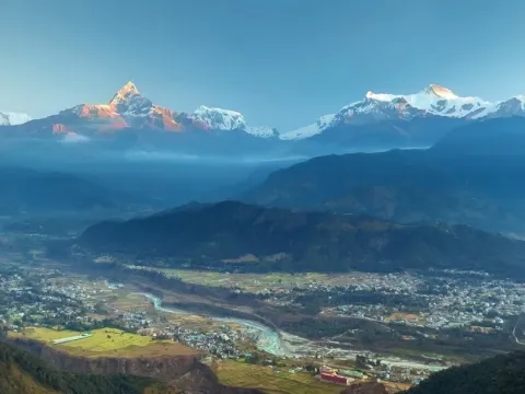 Golden sunrise over Himalayan mountain ranges and a scenic valley near Sarangkot, Nepal.