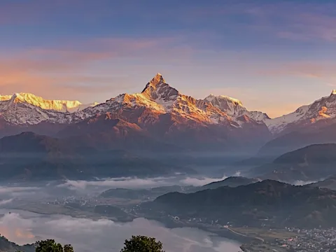 Golden sunrise over Himalayan mountain ranges and a scenic valley near Sarangkot, Nepal.