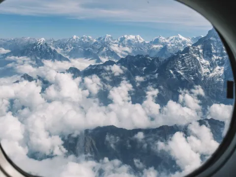 Snow-covered Himalayan mountains viewed through the aircraft window during an Everest mountain flight in Nepal.