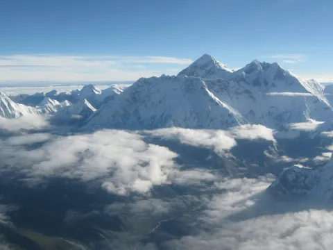 Snow-covered Himalayan peaks rising above a sea of clouds during an Everest mountain flight in Nepal.