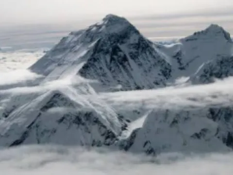 Majestic snow-capped Himalayan peaks emerging above the clouds during a scenic Everest mountain flight in Nepal
