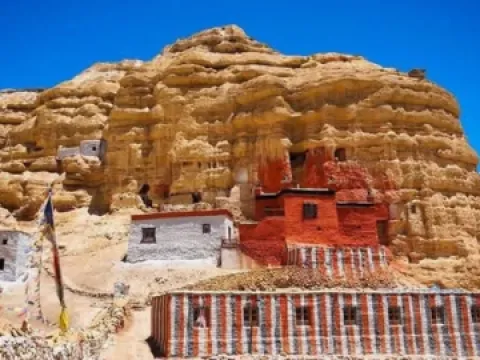 uAncient cliffside caves and traditional mud hoses in Upper Mustang, Nepal, surrounded by the dramatic Himalayan landscape.