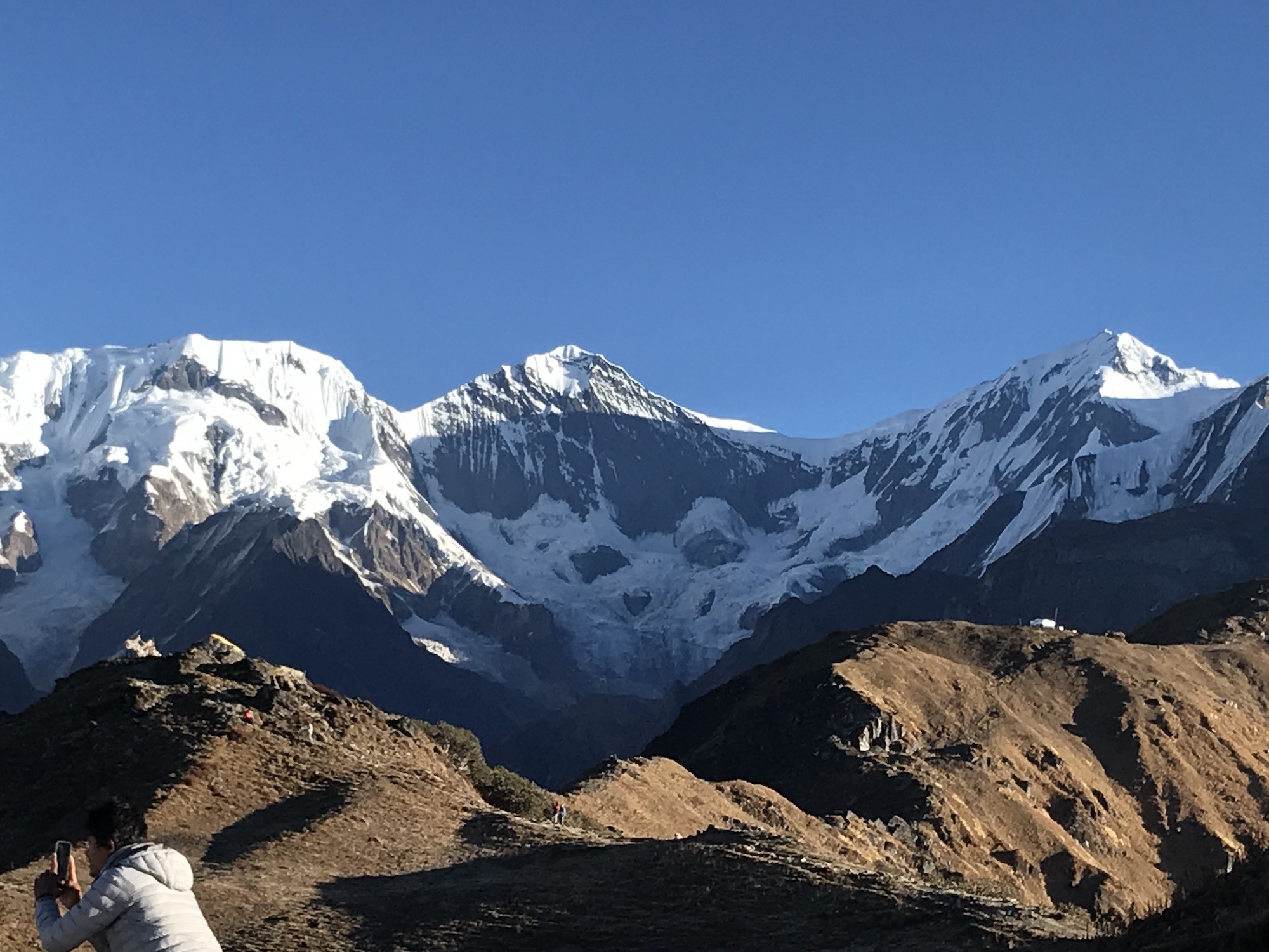 Trekker enjoying clear November weather on the Mardi Himal Trek with snow-capped Himalayan peaks, crisp blue skies, and warm layered clothing in the Annapurna region of Nepal. 