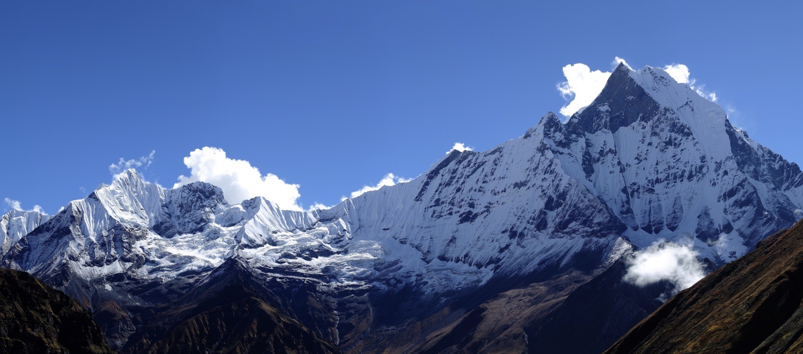 Machhapuchhre (Fishtail Mountain) rising above the Annapurna Base Camp trail with other snow-capped Himalayan peaks under a clear blue sky.