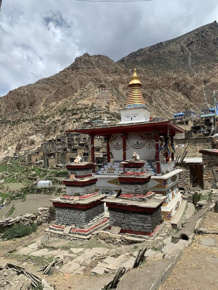 Ancient Buddhist stupa in the Himalayas of Nepal adorned with prayer flags, set against a backdrop of rugged mountains and clear alpine skies.