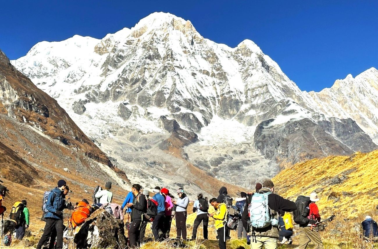 Crowded trail at Annapurna Base Camp in October with trekkers gathered among the dramatic Himalayan mountains.