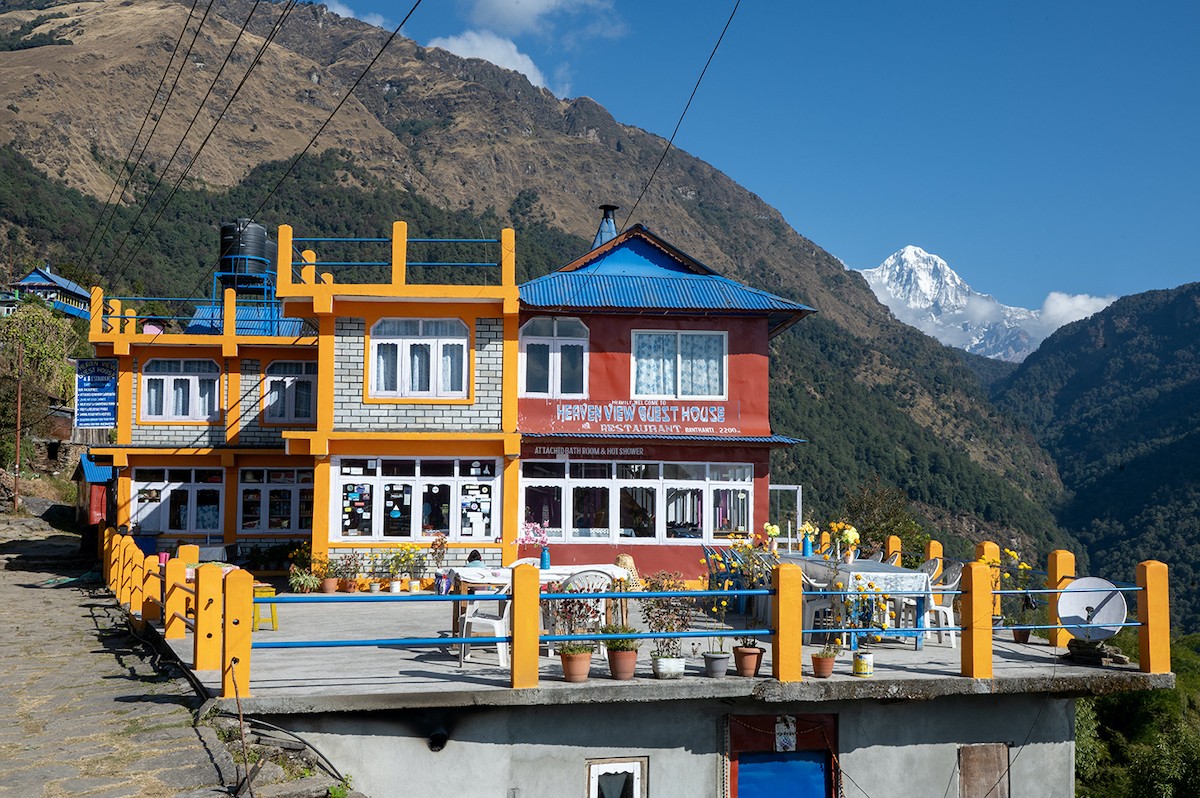 Mountain lodge on the Poon Hill Trek with stone architecture, colorful prayer flags, and stunning Himalayan scenery in Nepal's Annapurna region.