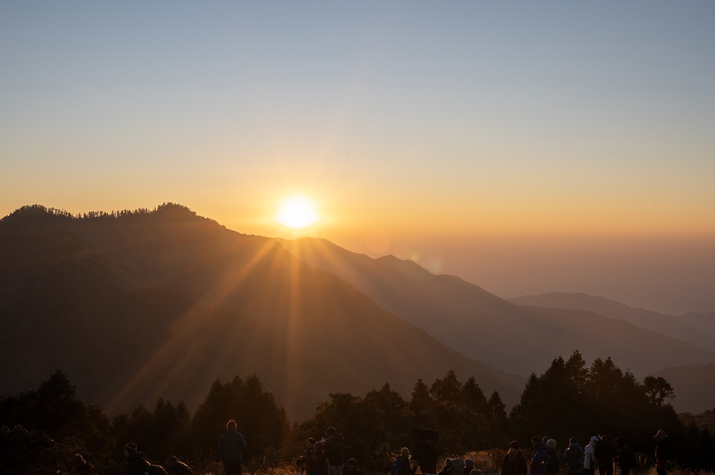 Golden sunrise view from Poon Hill with panoramic Himalayan peaks of Annapurna and Dhaulagiri illuminated in warm morning light above a sea of clouds.