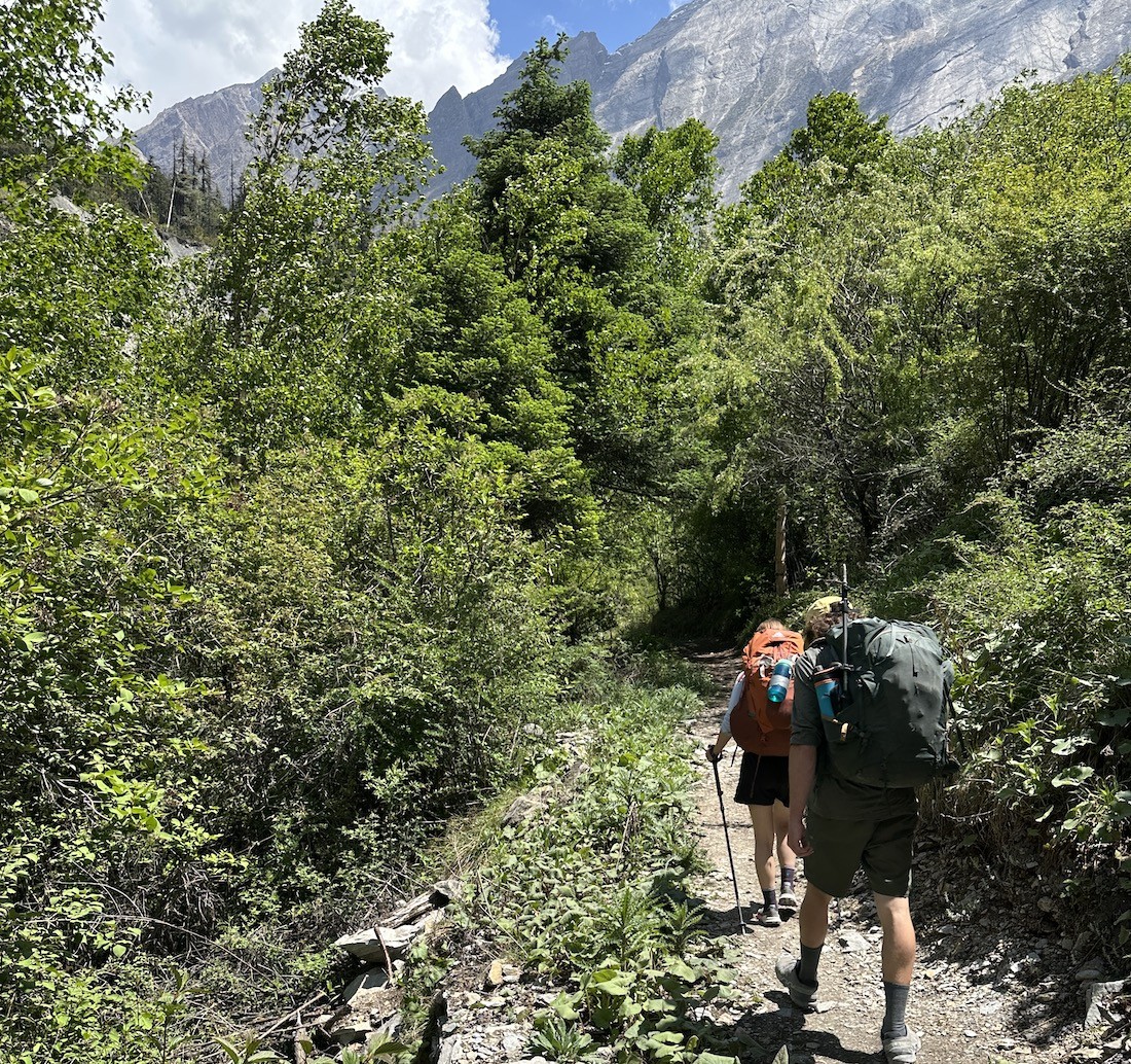 Dry trekking trail in October passing through lush green forests, terraced hillsides, and traditional mountain villages on the lower Annapurna Circuit, with clear blue skies and fresh post-monsoon scenery. 