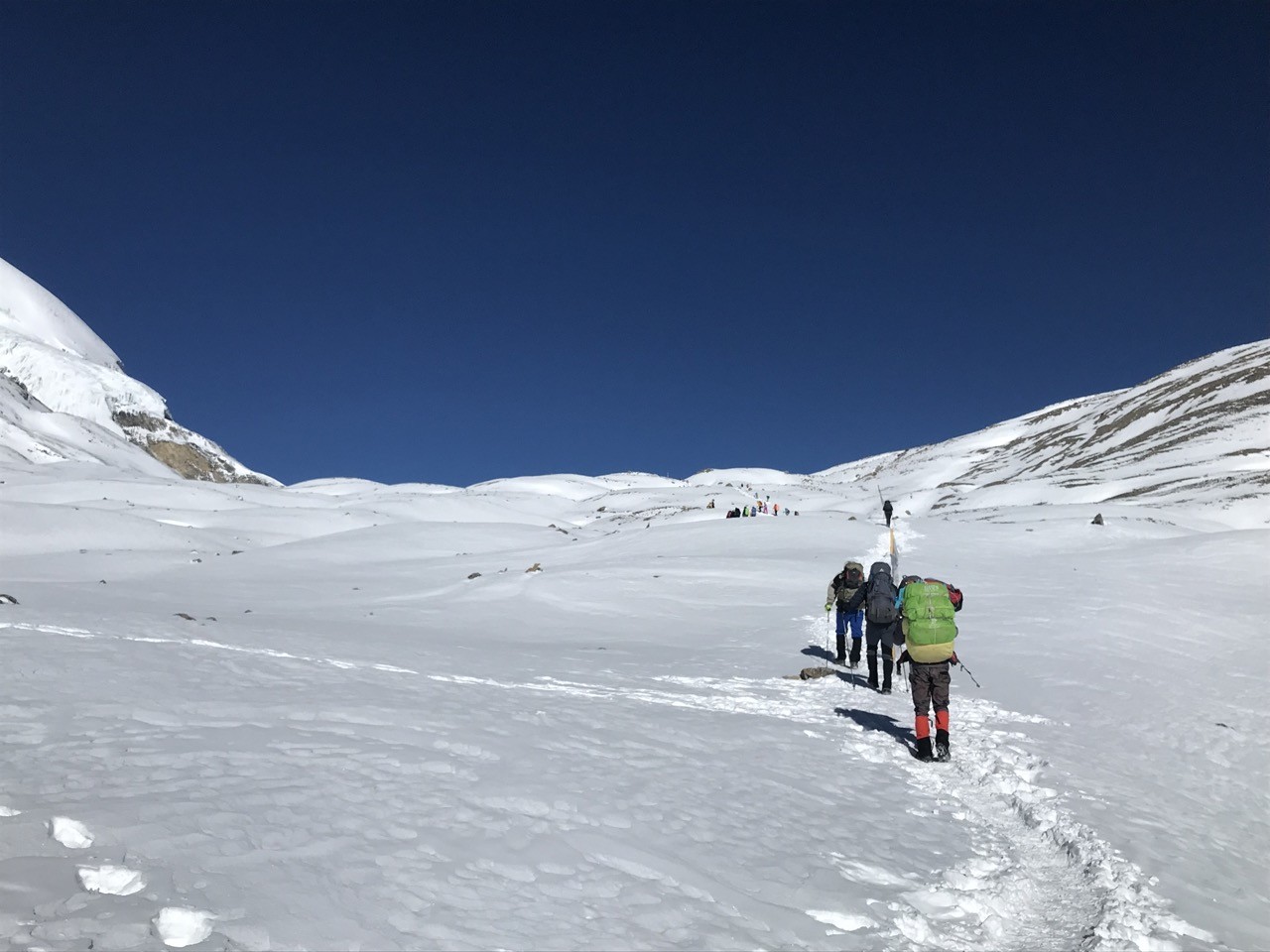 Trekkers heading toward Thorong La Pass on Annapurna Circuit snow trail Nepal Himalaya