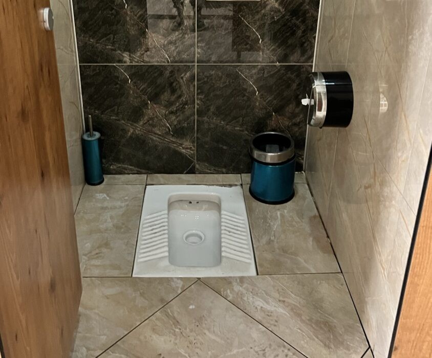 Basic squat toilet in a Himalayan teahouse lodge along a trekking route in Nepal, showing simple rural sanitation facilities used by trekkers in mountain regions.