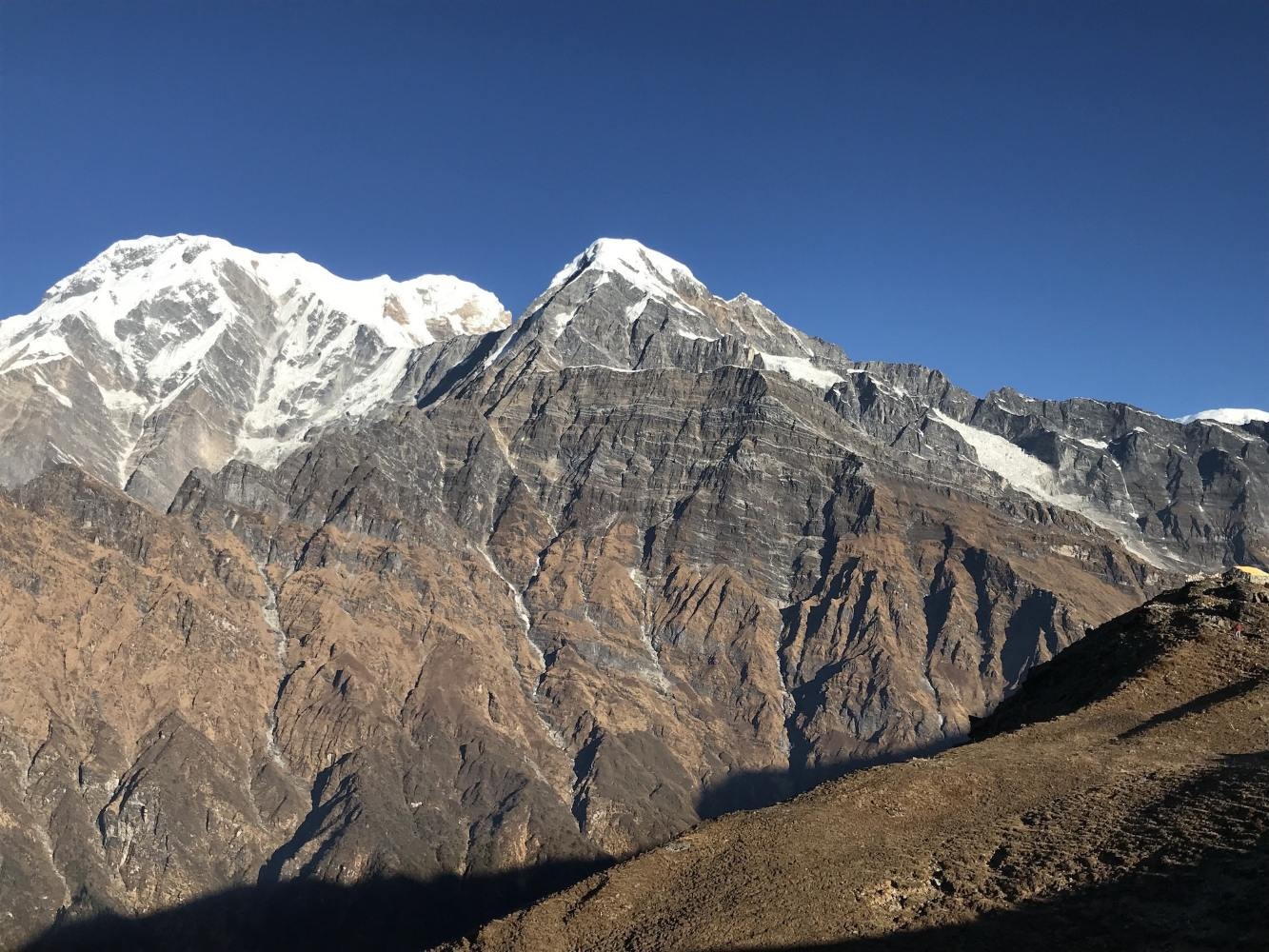View from Mardi Himal High Camp featuring Annapurna South, Hiunchuli, and mountain lodges in the Annapurna region of Nepal.