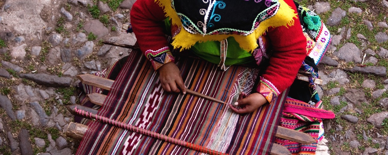  Traditional Himalayan textile weaving in Nepal showing local artisans hand-weaving fabric on a wooden loom using wool in a rural mountain village setting.