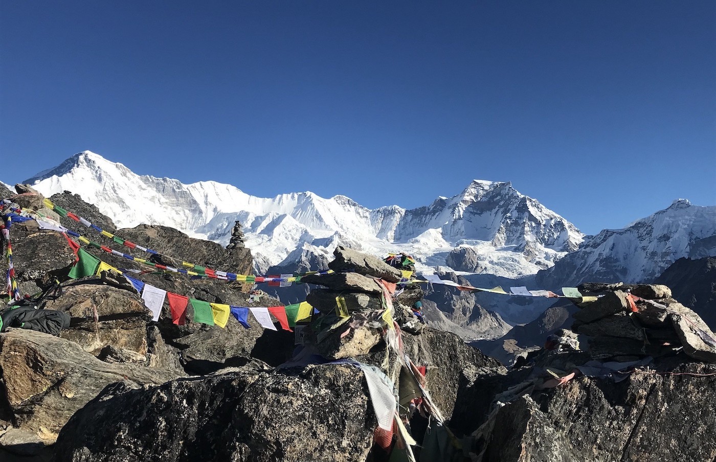 "Colorful Buddhist prayer flags on Gokyo Ri with Mount Cho Oyu rising above the turquoise Gokyo Lakes in Nepal's Everest region."