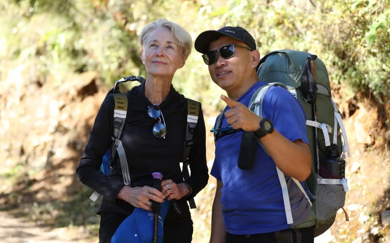 Licensed Nepali trekking guide accompanying a solo female trekker on a scenic Himalayan trail, ensuring a safe and enjoyable trekking experience in Nepal.