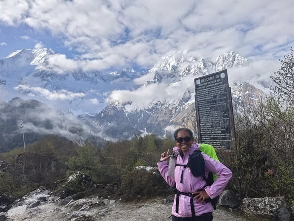 Solo female trekker hiking the Manaslu Circuit in Nepal, walking through stunning Himalayan landscapes with snow-capped peaks, traditional villages, and colorful prayer flags.