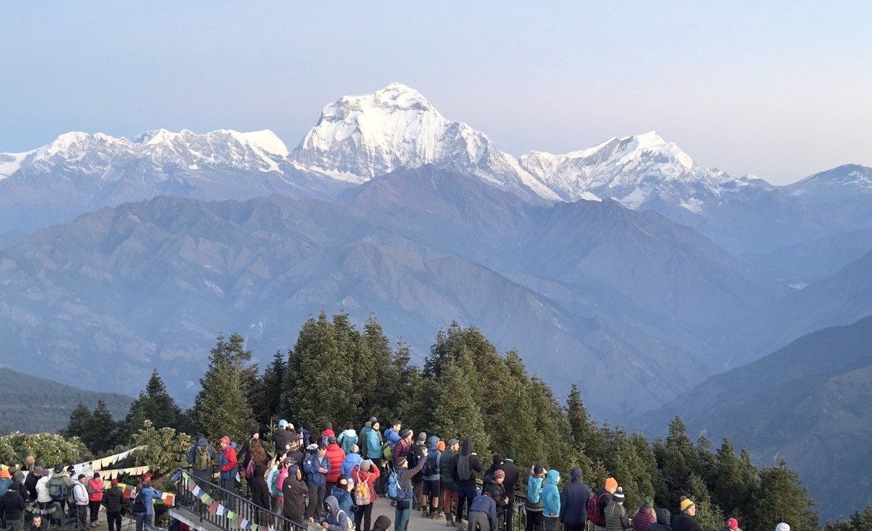 Trekkers enjoying panoramic Himalayan views from Poon Hill early morning in September with Dhaulagiri under clear autumn skies.