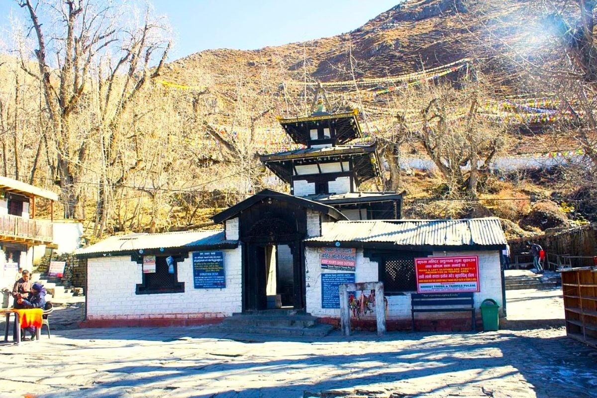 Sacred Muktinath Temple surrounded by snow-capped Himalayan peaks, colorful prayer flags, 108 water spouts, and pilgrims visiting one of Nepal's most revered Hindu and Buddhist pilgrimage sites