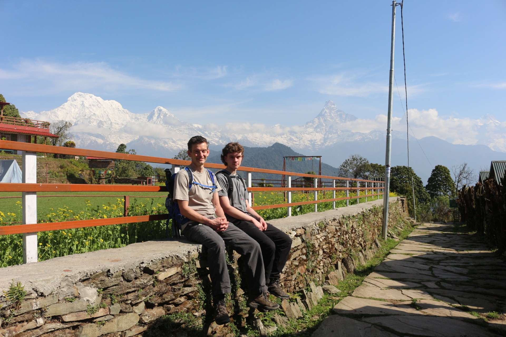 Trekkers enjoying a rest stop on the Mardi Himal Trek in September with panoramic views of Machhapuchhre (Fishtail Mountain), Annapurna South, and lush post-monsoon landscapes in the Annapurna region of Nepal." 