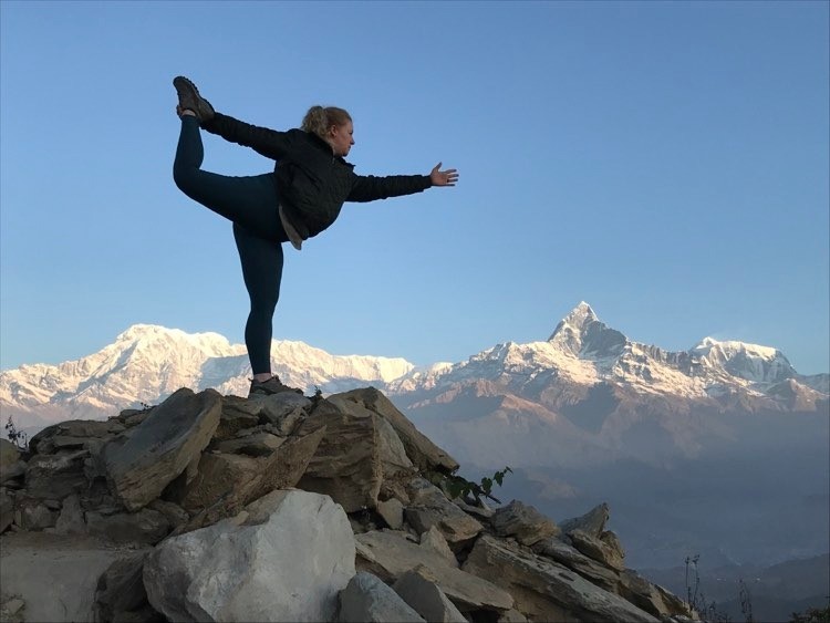 Trekkers posing on a Himalayan viewpoint in Nepal with a spectacular snow-capped mountain range stretching across the background under a clear blue sky.