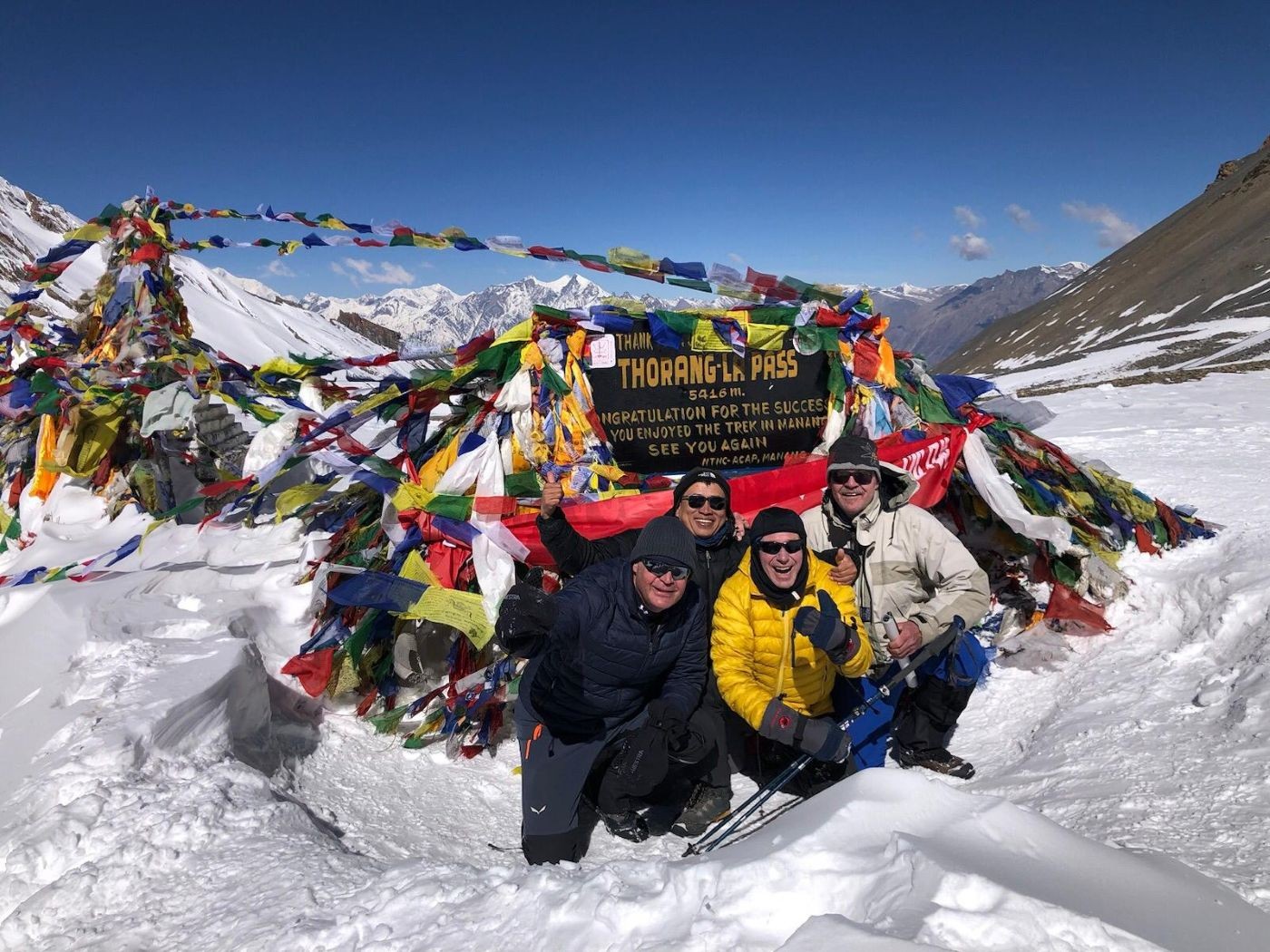 Summit of Thorong La Pass in winter with snow-covered trail and trekkers on Annapurna Circuit Nepal Himalaya