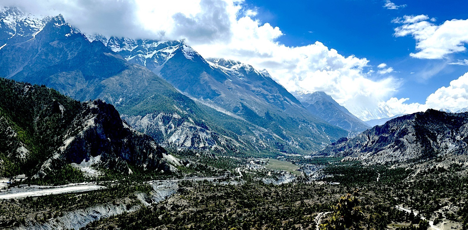 Wide view of Manang Valley in the Annapurna region, showing alpine terrain with dry hills, snow-capped Himalayan peaks, scattered settlements, and dramatic high-altitude landscapes.