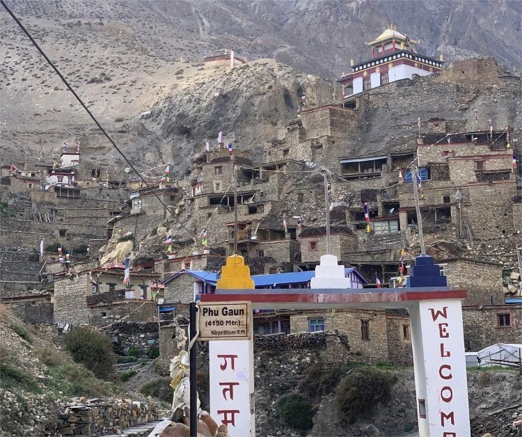 Phu Gaun village in Nar Phu Valley Nepal showing traditional stone houses, village gate with three symbolic stupas on top and nearby Buddhist monastery in remote Himalayan region