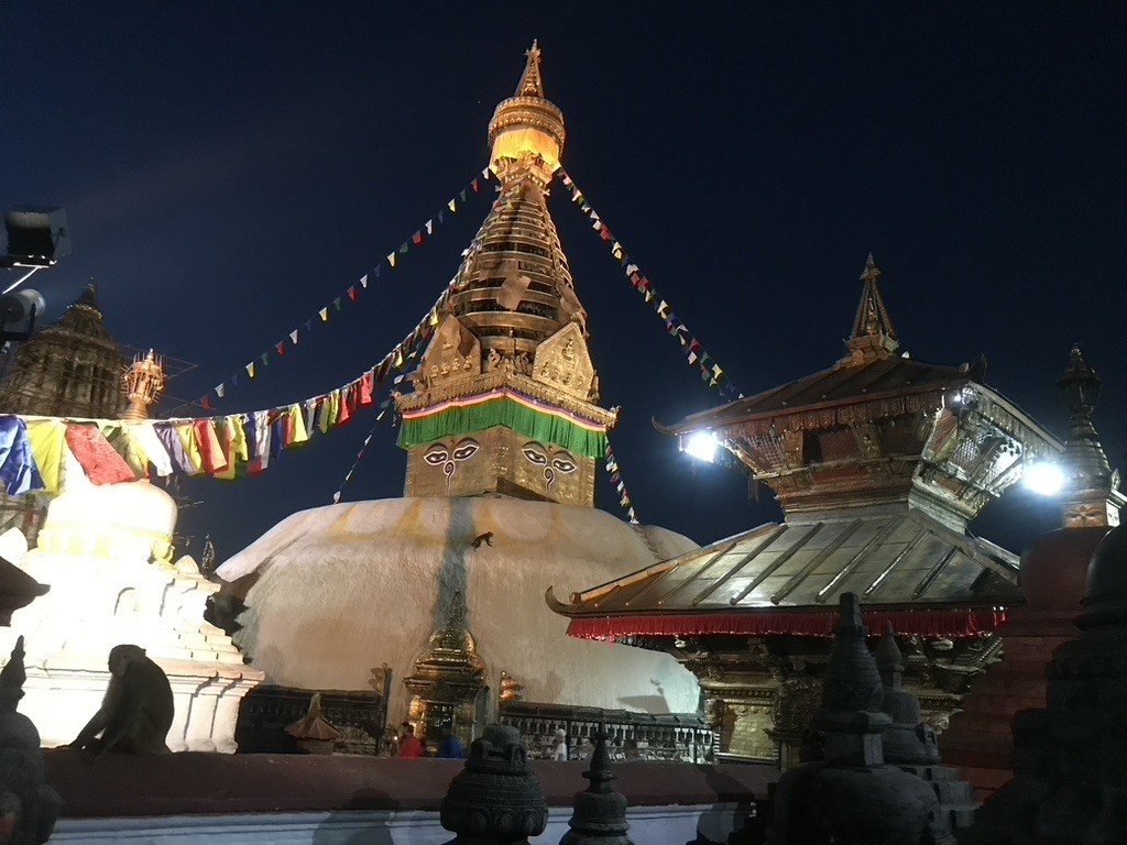 Swayambhunath Stupa with its iconic Buddha eyes, golden spire, white dome, and colorful prayer flags overlooking Kathmandu Valley, Nepal.