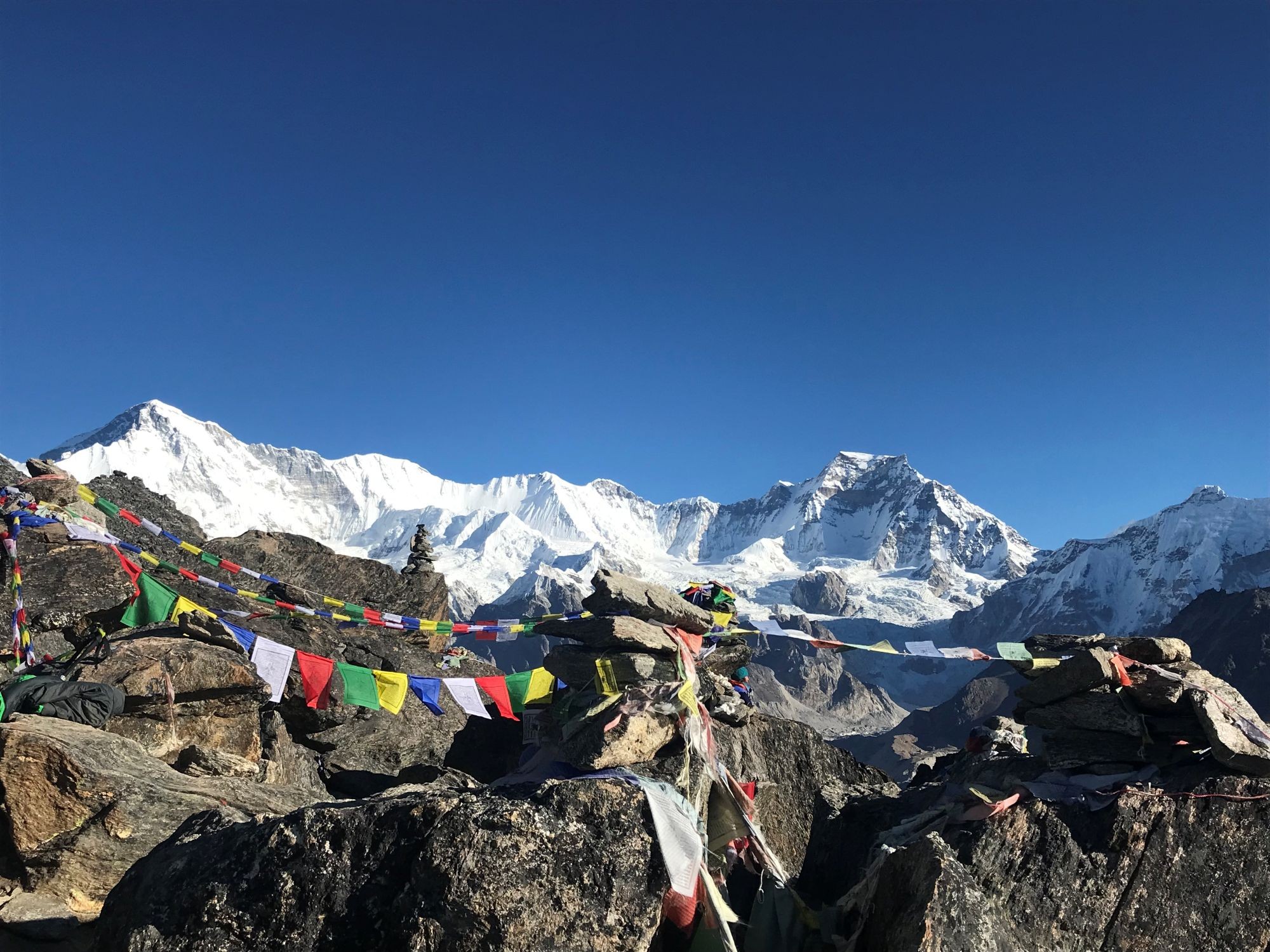 Hikers ascending Gokyo Ri with panoramic views of Gokyo Lakes, Cho Oyu, Mount Everest, and the snow-covered Himalayas.