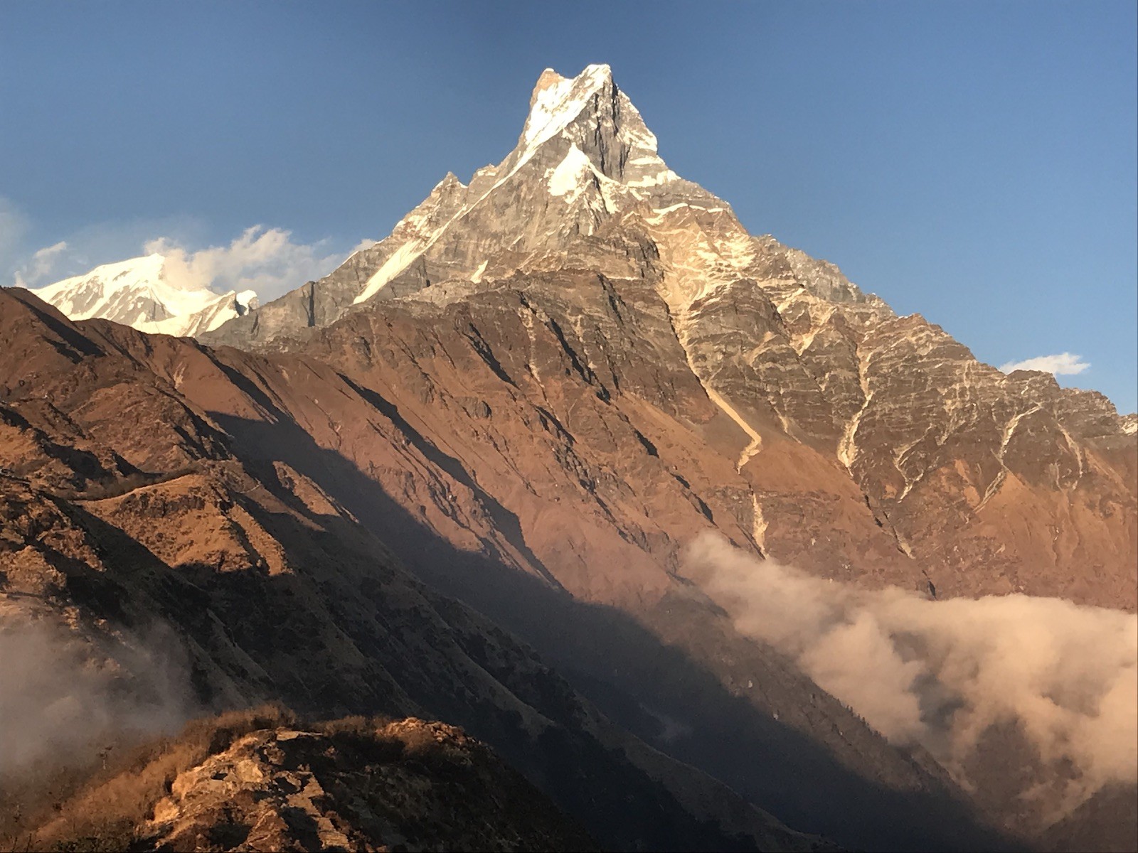 the iconic Machhapuchhre (Fishtail) Mountain with drifting clouds below, captured from the Mardi Himal Trek in autumn, showcasing crystal-clear October weather and spectacular Himalayan scenery