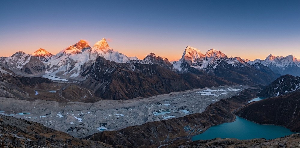 Panoramic view from Gokyo Ri featuring Gokyo Lakes, Ngozumpa Glacier, Mount Everest, Lhotse, Makalu, and Cho Oyu under clear blue skies in Nepal's Everest region.