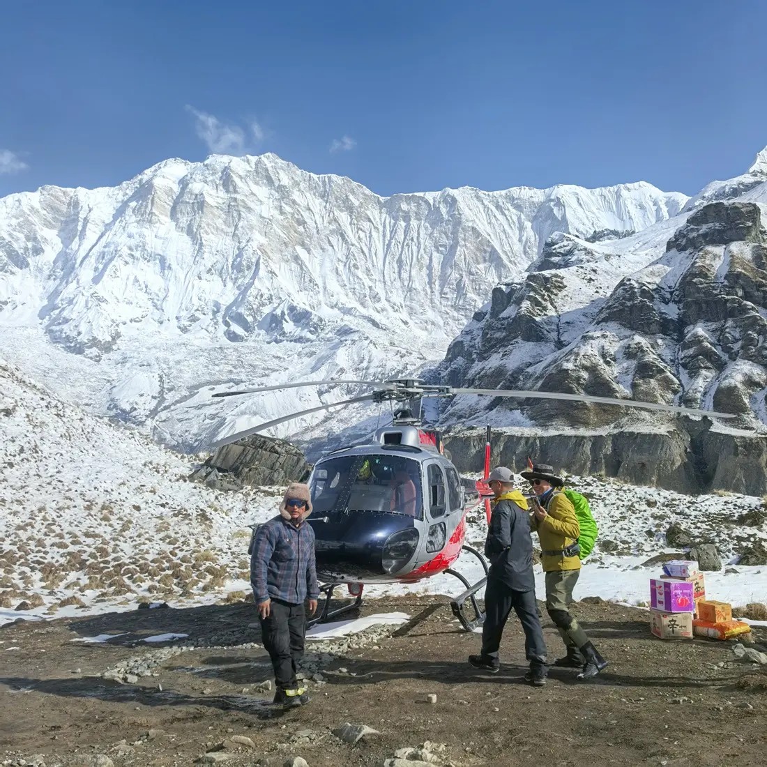  helicopter taking off from Annapurna Base Camp, soaring above the Annapurna Sanctuary with panoramic views of Annapurna I, Machhapuchhre (Fishtail Mountain), glaciers, and snow-covered Himalayan peaks