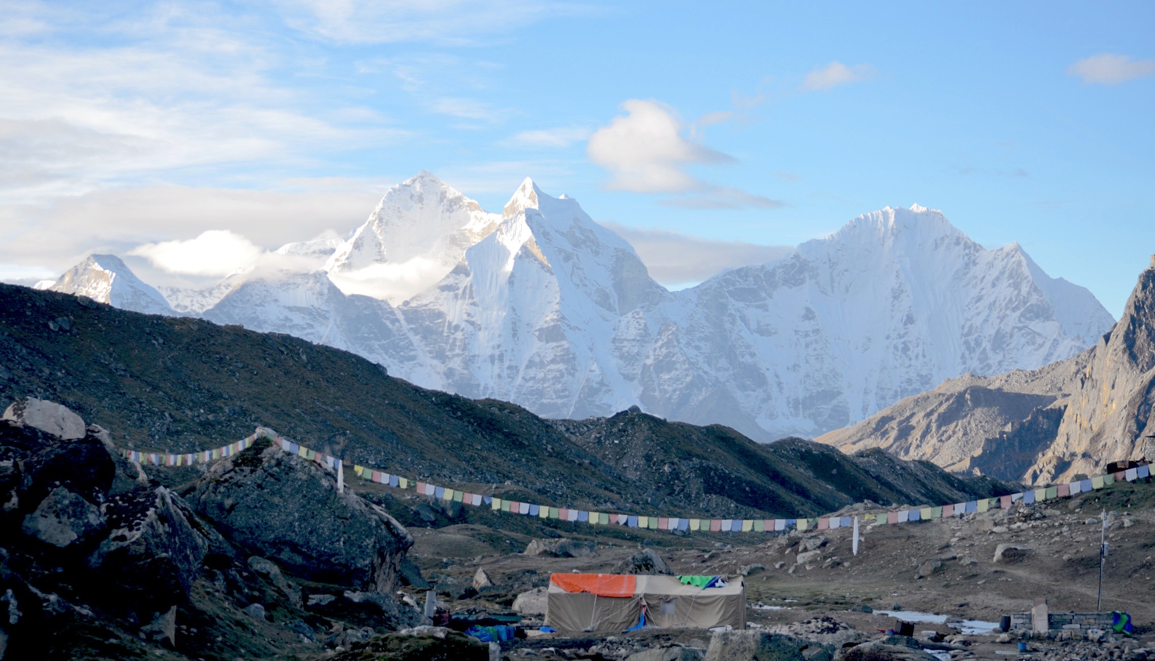 High-altitude trekking route in the Everest region of Nepal showing the trail from Dingboche to Lobuche passing through Thukla Pass with rocky moraine terrain, memorial chortens, and snow-covered Himalayan peaks.