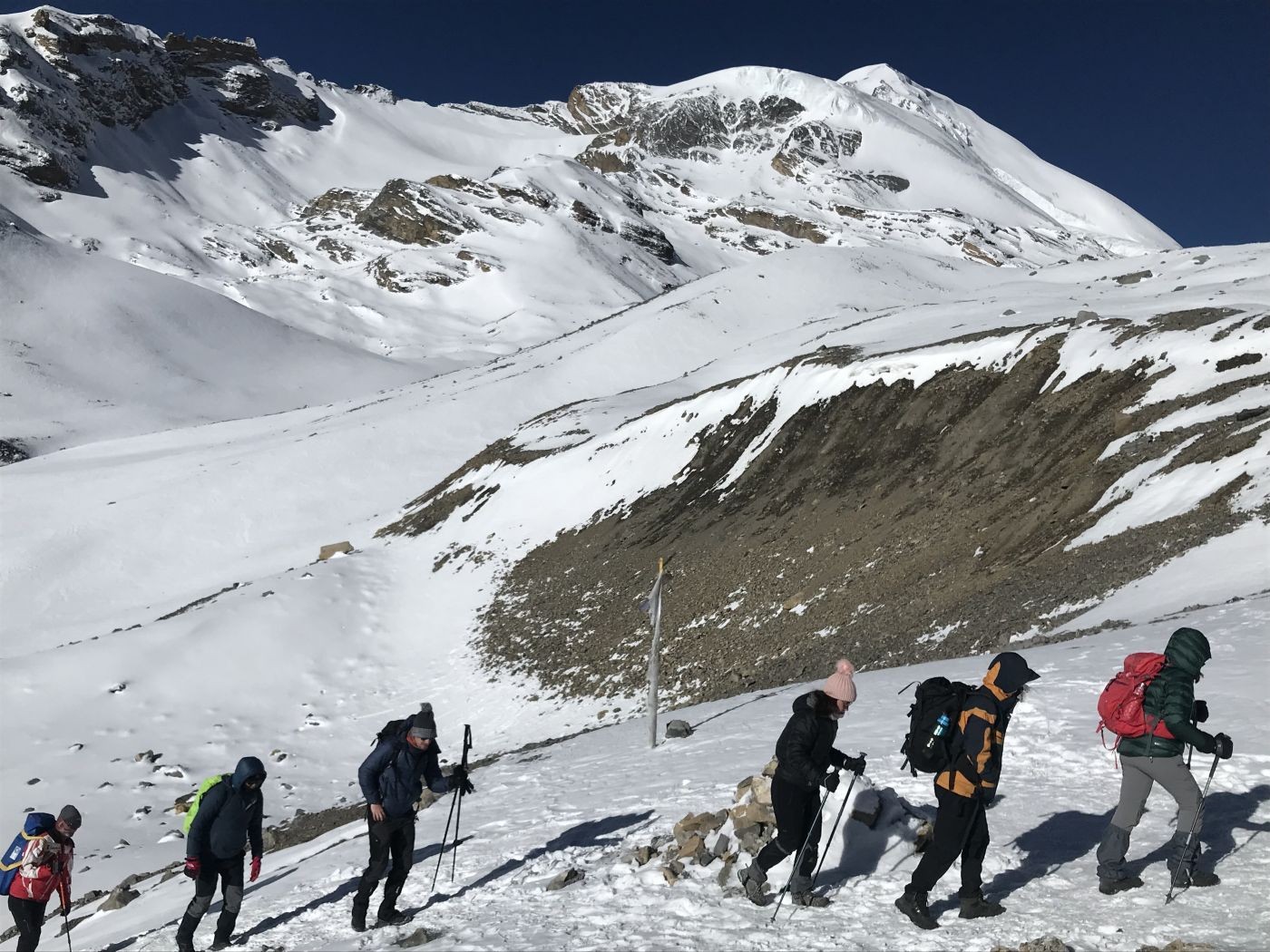 Guided trekkers hiking on Annapurna Circuit Nepal with professional guide and porters in Himalayan mountains