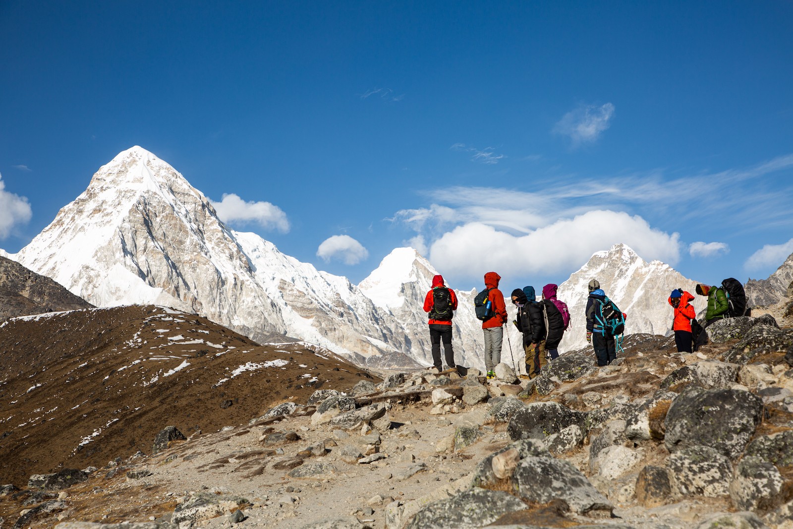"Trekker wearing layered clothing, down jacket, hiking pants, gloves, beanie, and trekking boots on the Everest Base Camp Trek in November" 